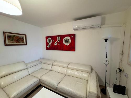 a living room with a white couch and a painting at Comfort on the ground in Haifa