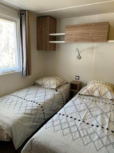 une chambre avec deux lits et une fenêtre dans l'établissement Mobilhome Landes Les Dunes de Contis, à Saint-Julien-en-Born