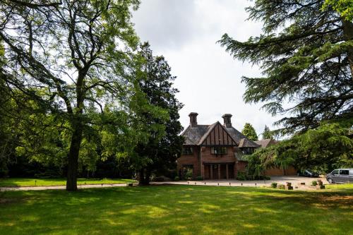 an old house with a green lawn and trees at Chimneys Hot Tub Country Escape in Stourbridge