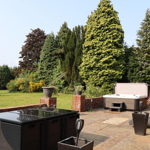 a backyard with a barbecue grill and trees at Chimneys Hot Tub Country Escape in Stourbridge