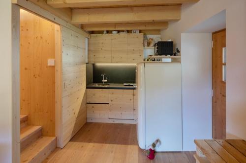 a kitchen with a refrigerator and wooden walls at La casa nel Borgo - Cà Rezzuò 61 in Vodo Cadore