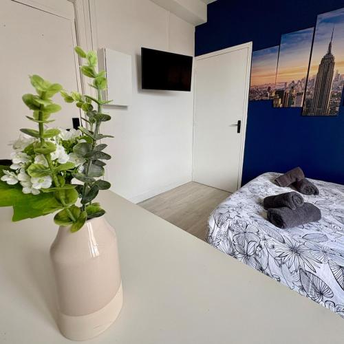 Cette chambre dispose d'un vase avec des fleurs sur une table. dans l'établissement Dalikyda - Manhattan - Free Parking, au Havre
