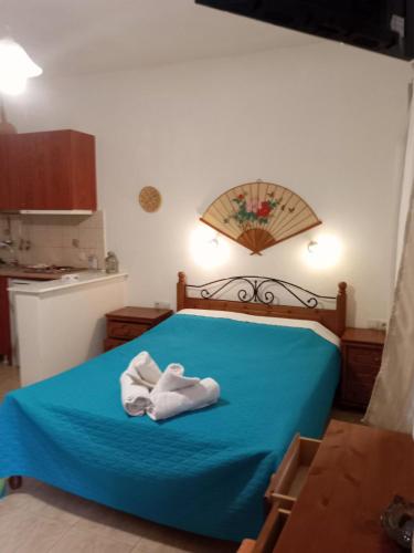 a bedroom with a blue bed with towels on it at Kouvaras Apartments in Kýthira