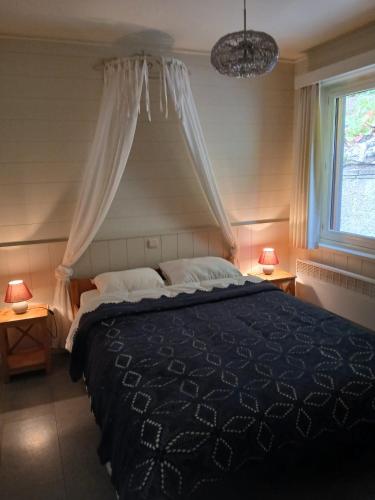 a bedroom with a bed with a black comforter and a window at Le silence de Frahan in Bouillon