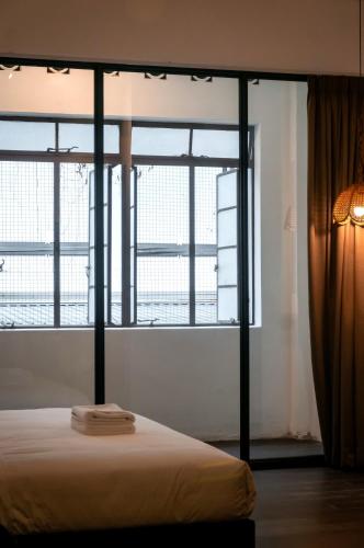 a bedroom with large windows and a white bed at Aayu Chowrasta - 3 mins walk to Penang Road Chendul in George Town