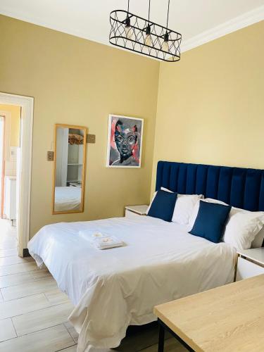 a bedroom with a large bed with a blue headboard at Henry George Hotel in Pretoria