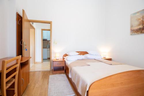 a bedroom with a bed and a desk with two lamps at Villa Alesa Steva in Tučepi