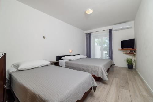 two beds in a hotel room with a window at Apartments Jadranka in Dramalj