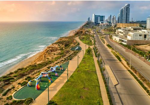 a beach with a road and the ocean and buildings at Vila first line to the sea in Netanya