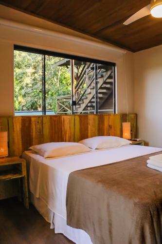 a bedroom with a large bed and a window at Bossa Beach House in Ilha do Mel