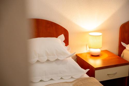 a bedroom with a bed with white pillows and a lamp at Villa Alesa Steva in Tučepi