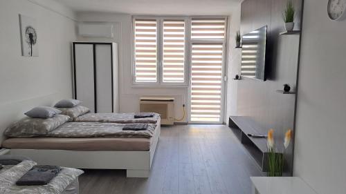 a room with two beds and a door with windows at White Harmony Apartment in Debrecen