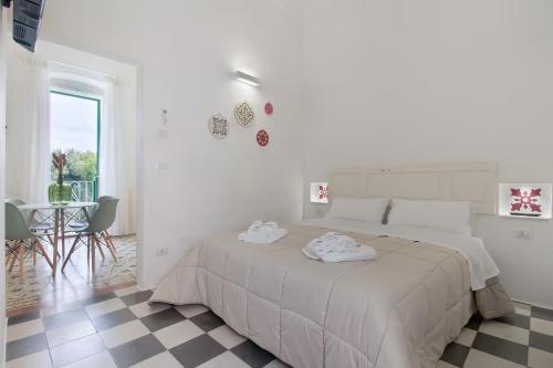 a white bedroom with a large bed and a table at Le Cementine - Apulian Rooms in Fasano