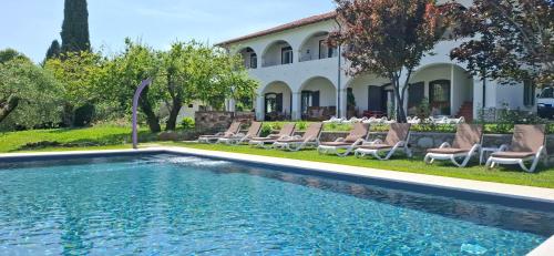 una piscina con sedie e una casa sullo sfondo di La Kascina Suite & Rooms a Moniga
