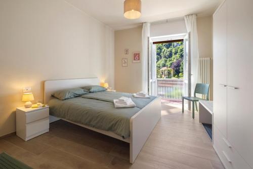 a bedroom with a bed and a large window at Maison Petrolini - Maggiore Estate by Ginin in Cannobio