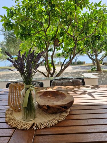 a wooden table with a plate and a vase with flowers at Apartman Lucija in Seline