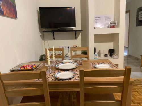 a dining room table with four chairs and a television at City Center Apartment in Ioannina