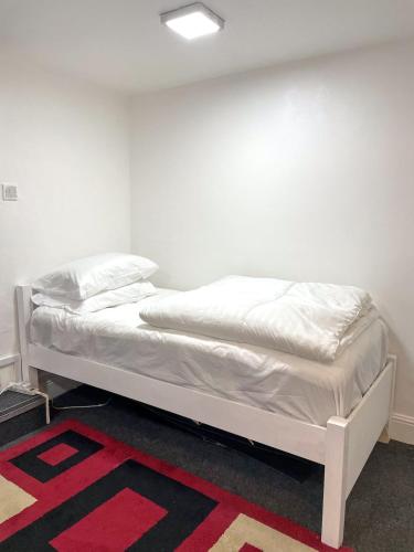 a white bed in a room with a red rug at Large Studio Flat in heart of Camden market in London