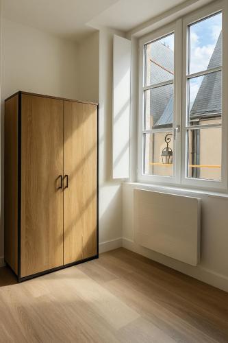 une grande armoire en bois dans une chambre avec deux fenêtres dans l'établissement Studio Cosy - Doutre Centre Angers, à Angers