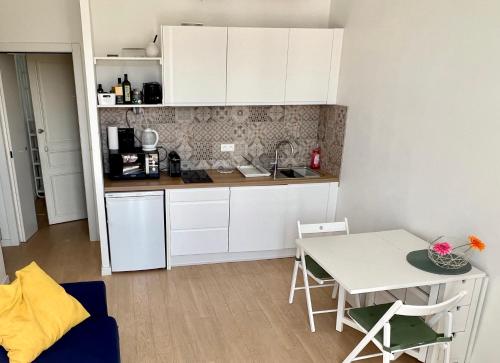 une petite cuisine avec des armoires blanches et une table dans l'établissement Charming apartment in the heart of Cannes, à Cannes
