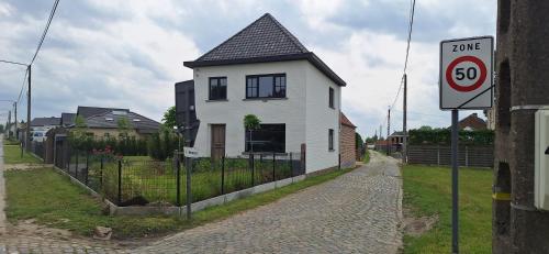 a white house with a black roof on a street at Vakantiehuis 't Ketsken - Gavere in Gavere