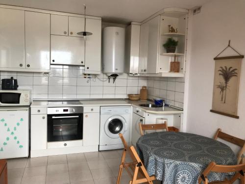 a kitchen with white cabinets and a table and a dishwasher at Apartamento Somo Vistamar in Somo