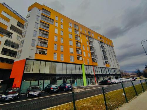 duży budynek z zaparkowanymi przed nim samochodami w obiekcie Apartment Clover Sarajevo w Sarajewie