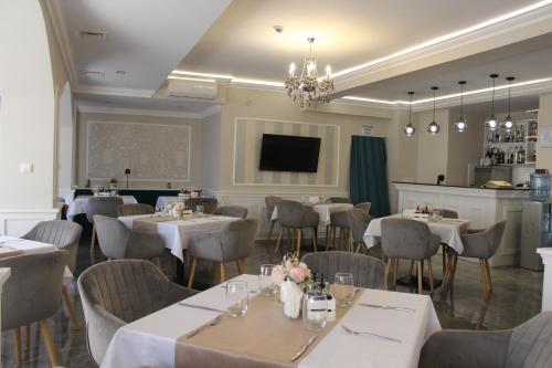 a dining room with tables and chairs and a television at Vemara City Boutique Hotel-free parking in Varna City