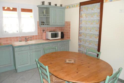 une cuisine avec une table en bois et un micro-ondes dans l'établissement Gîte 8 Personnes Piscine Privée Aude Occitanie Sud Corbières, à Fabrezan