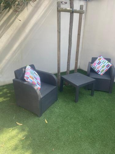 two chairs and a table in a room with grass at Maison Cosy avec Jacuzzi in Le Grau-du-Roi