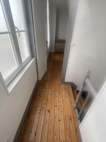 un couloir vide avec du parquet et une fenêtre dans l'établissement Maison Royan, à Royan