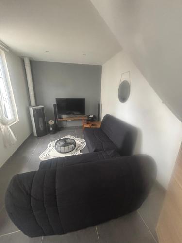 un salon avec un canapé noir et une télévision dans l'établissement Maison Royan, à Royan