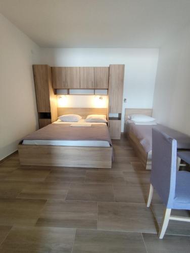 a bedroom with two beds and a blue chair at Apartmani Frane in Seline