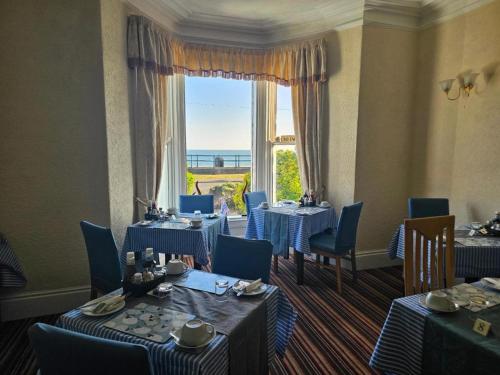 St. Hilary Guest House في خلنددنو: مطعم بطاولات وكراسي ونافذة كبيرة