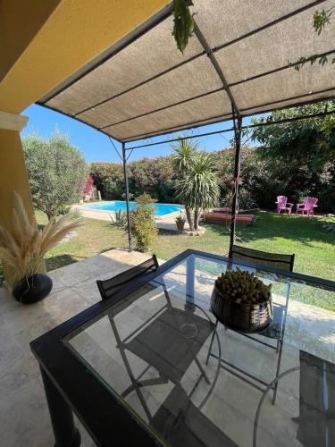 une terrasse avec une table et des chaises en verre ainsi qu'une piscine dans l'établissement Maison de vacances, au Thor