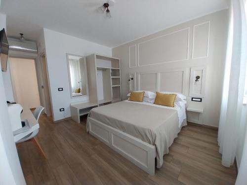 a white bedroom with a large white bed with yellow pillows at Le Camere di Libero e Roberta in Tropea