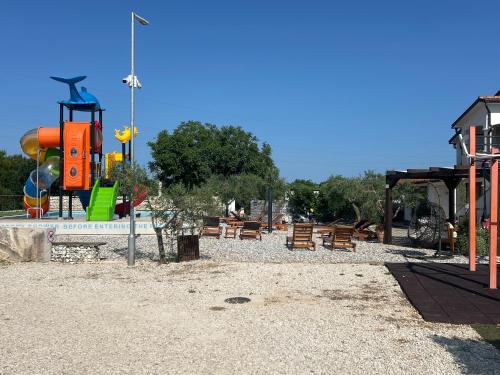 a park with a playground with a slide and benches at Large camper in the olive grove in Banjole