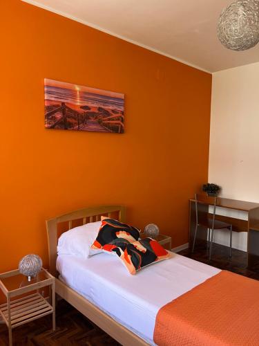 a bedroom with an orange wall with a bed at B&B Lary in Pescara