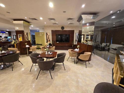 a restaurant with tables and chairs and a television at Ekono Hotel in Jeddah