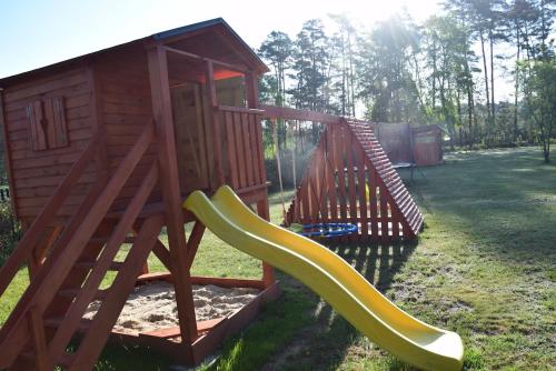 a playground with a slide and a play house at Chata w lesie in Zagwiździe