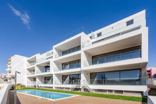 a white apartment building with a swimming pool at Hibisco is a modern apartment, 5min walk to beach in Luz