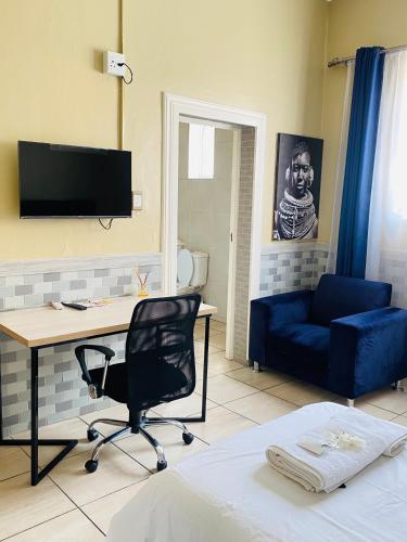 a living room with a desk and a blue couch at Henry George Hotel in Pretoria