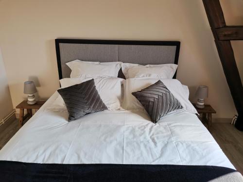 - un lit avec des draps et des oreillers blancs dans l'établissement L'église, à Sainte-Marie-au-Bosc