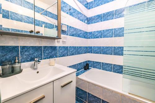 une salle de bain carrelée bleue avec un lavabo et une baignoire dans l'établissement Peaceful Flat in Montorgueil, à Paris