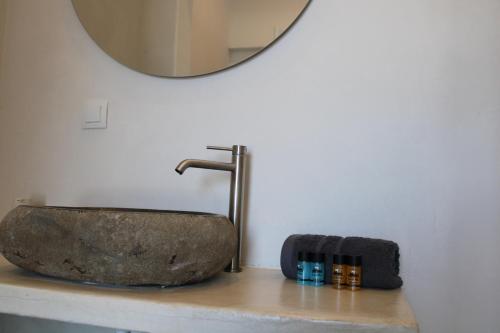 a bathroom with a stone sink and a mirror at Lefkes Beach Suite in Kithnos