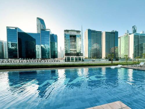 a swimming pool with a city skyline in the background at Luxury Apartment with Balcony & Full Burj Khalifa View by Dejaview Stays in Dubai
