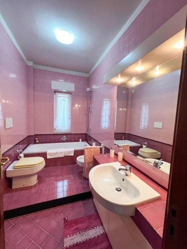 a pink bathroom with a tub and two toilets and a sink at Domus Ortensia in Boscoreale