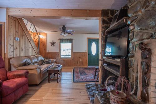 a living room with a couch and a stone fireplace at Buffalo Creek Cabin- Hot Tub Creekfront Escape in Robbinsville