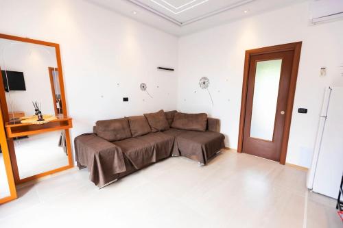 a brown couch in a white room with a mirror at Oasi verde con terrazzo e parcheggio gratuito in Zolforata