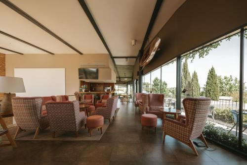 a lobby with chairs and tables and large windows at Herdade da Cortesia Hotel in Avis